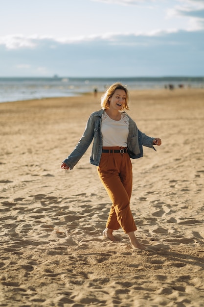 young girl in denim jacket  enjoy sun on beach on summer evening