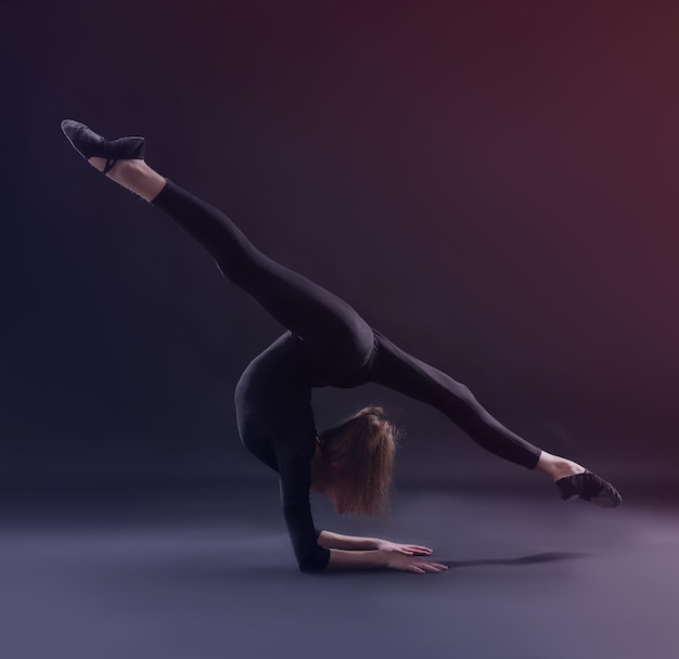 Young girl doing gymnastics on dark background