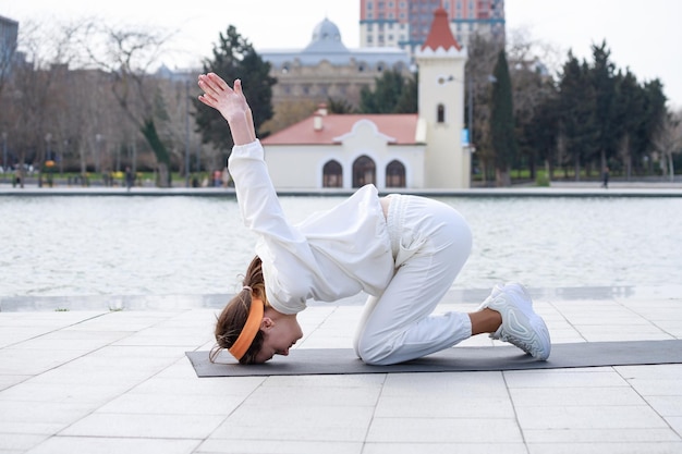 Young girl doing her exercises on mat in front of lake High quality photo