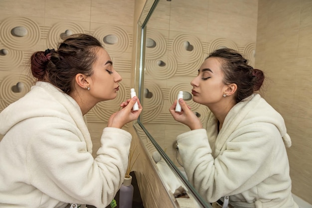 Young girl doing makeup for herself in the evening in the bathroom in home clothes