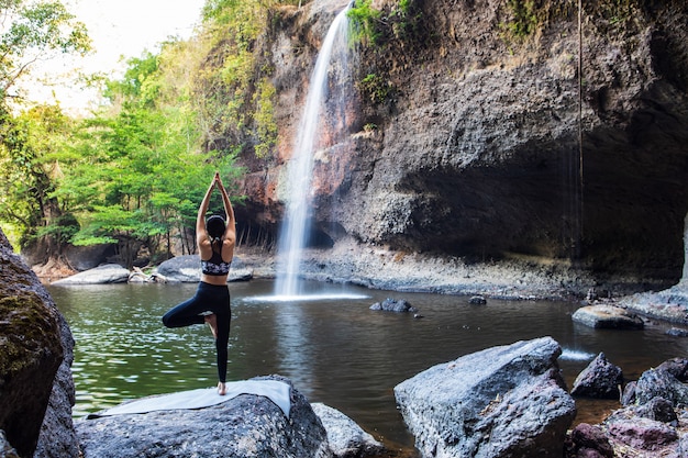 Young girl doing yoga near a waterfall