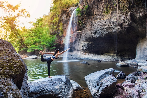 Young girl doing yoga near a waterfall