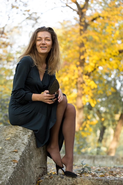 A young girl in dress poses in a park on a background of golden autumn foliage