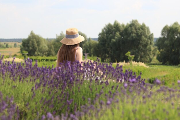 A young girl in a dress sits on green grass in a natural park on a summer day Spend time alone