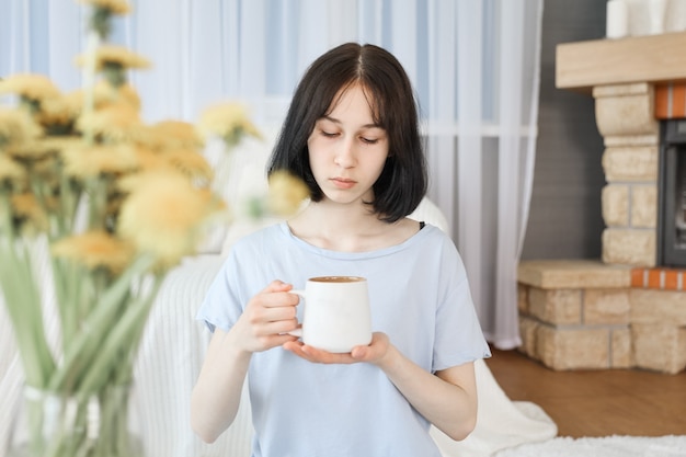 A young girl drinks tea in the living room