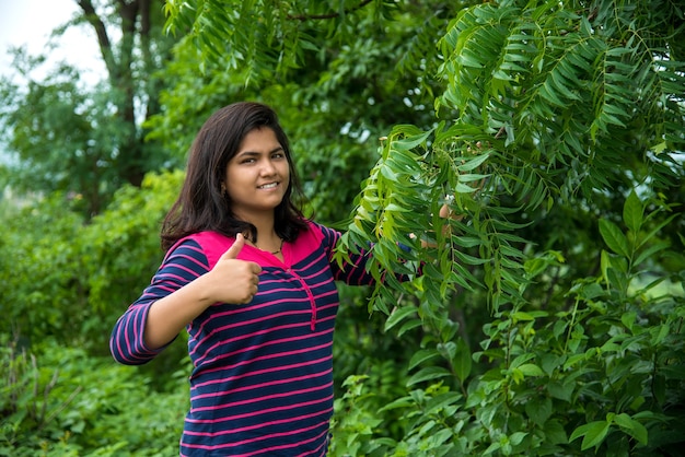 Young girl examine or observing Neem Tree leaf at field