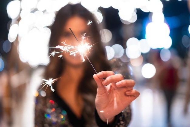 Young girl in a fashionable dress with sequins in the city christmas lights