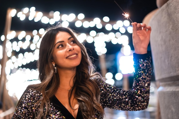 Young girl in a fashionable dress with sequins in the city christmas lights