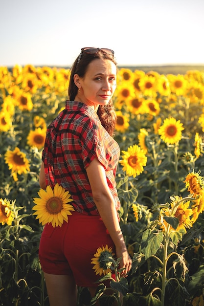 A young girl in a field of sunflowers at sunset Portrait of a woman with a slim figure on a background of yellow flowers