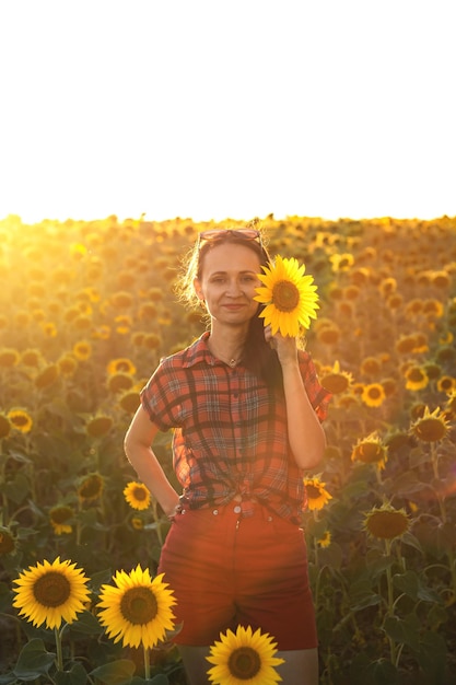 A young girl in a field of sunflowers at sunset Portrait of a woman with a slim figure on a background of yellow flowers