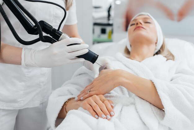 A young girl gets carbon peeling for the skin of her hands in a beauty salon Laser pulses cleanse the skin Hardware cosmetology The process of photothermolysis warming the skin