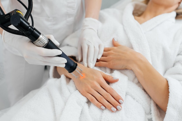 A young girl gets carbon peeling for the skin of her hands in a beauty salon Laser pulses cleanse the skin Hardware cosmetology The process of photothermolysis warming the skin