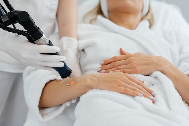 A young girl gets carbon peeling for the skin of her hands in a beauty salon Laser pulses cleanse the skin Hardware cosmetology The process of photothermolysis warming the skin