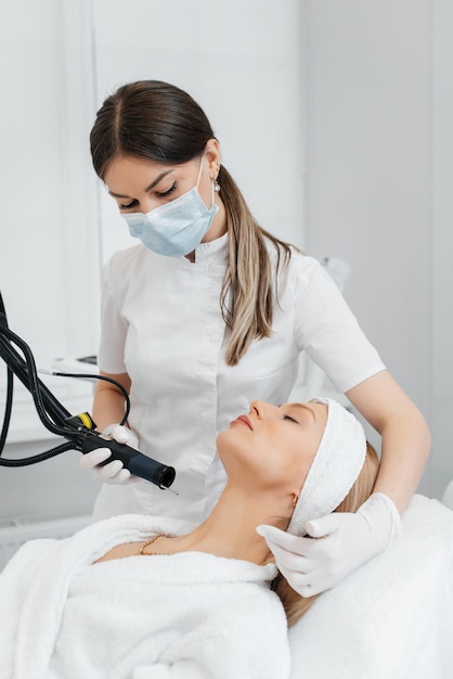 A young girl gets a carbon peeling for the skin of the neck in a beauty salon Laser pulses cleanse the skin Hardware cosmetology The process of photothermolysis warming the skin