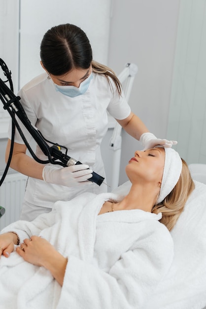 A young girl gets a carbon peeling for the skin of the neck in a beauty salon Laser pulses cleanse the skin Hardware cosmetology The process of photothermolysis warming the skin