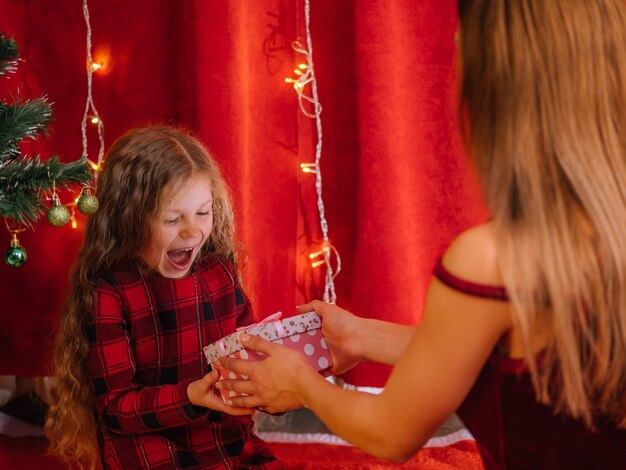 Young girl gets present from mother Christmas time at home