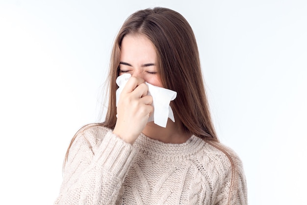 Young girl gets sick and wipes the nose is isolated on a white background