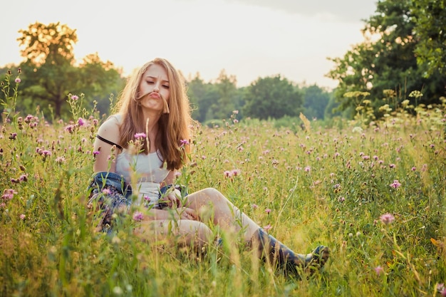 Photo young girl on grass in the meadow having fun playing with hair and making faces funny grimace