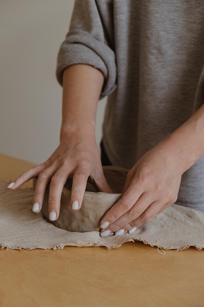 A young girl in a grey long sleeve makes a vase of clay with her own hands in a sculpture workshop