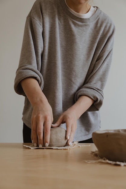 Photo a young girl in a grey long sleeve makes a vase of clay with her own hands in a sculpture workshop