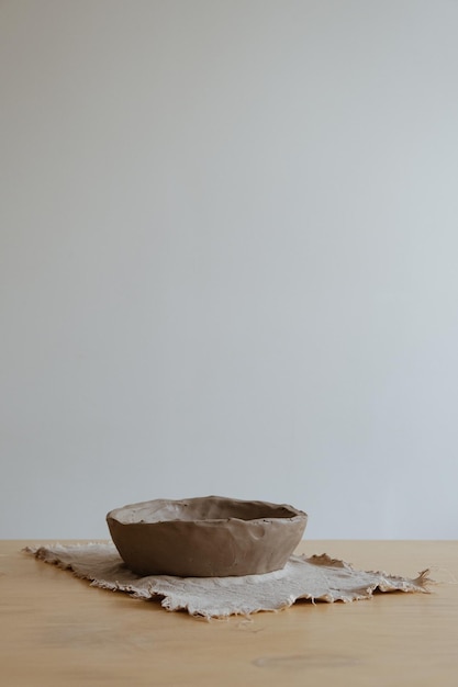 A young girl in a grey long sleeve makes a vase of clay with her own hands in a sculpture workshop