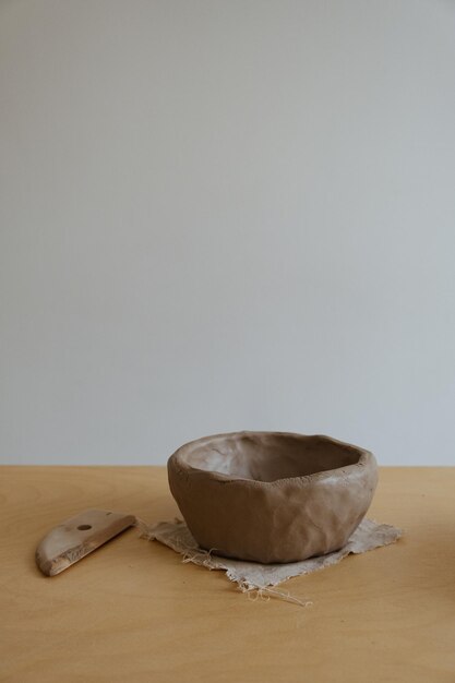 A young girl in a grey long sleeve makes a vase of clay with her own hands in a sculpture workshop