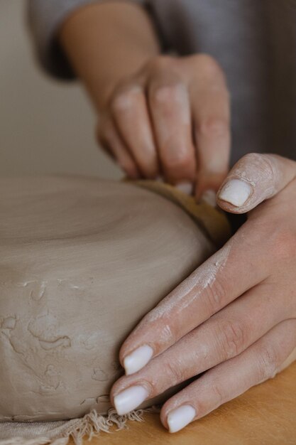 A young girl in a grey long sleeve makes a vase of clay with her own hands in a sculpture workshop