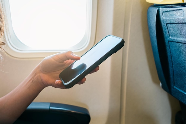 Young girl hand using smartphone on airplane