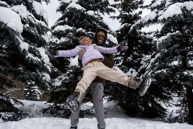 Young girl having fun with her father on a snowy winter day