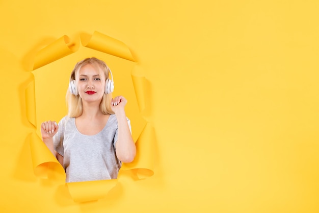 Young girl in headphones on torn yellow paper surface