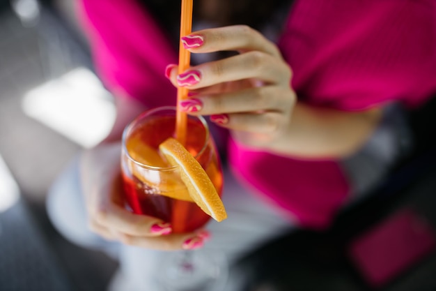 Young girl holding an aperol spritz Cocktail aperol spritz in a glass Young girl in a restaurant with a glass Aperol spritz in the hands of a girl Aperol spritz Cocktail