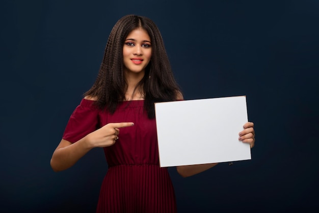 A young girl holding a blank white billboard or signboard in her hands on a gray background