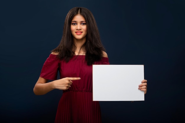 A young girl holding a blank white billboard or signboard in her hands on a gray background