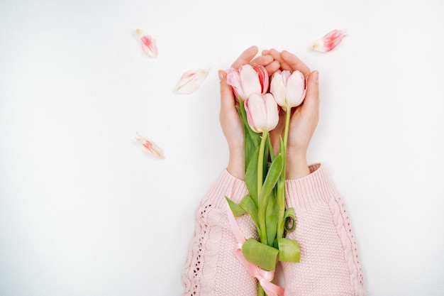 Young girl holding a bouquet of pink tulips. Top view, white background, text copy space.