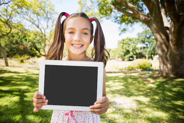 Young girl holding digital tablet in park