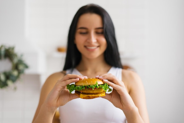 Young girl holding a fastfood burger in female hands unhealthy highcalorie food a layout with a copy space