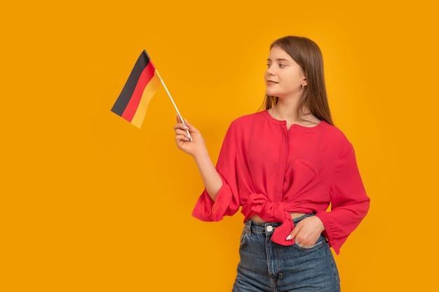 Young girl holding flag of Germany on an orange background Schoolgirl of Germany Learn German Student Exchange Program