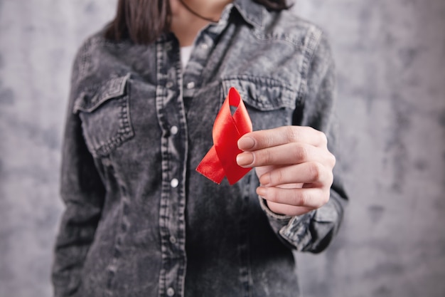 Photo young girl holding a red aids ribbon in her hands