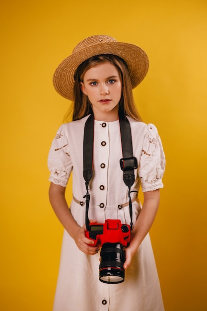 Young girl holding a red camera in her hands and looking at the photographer