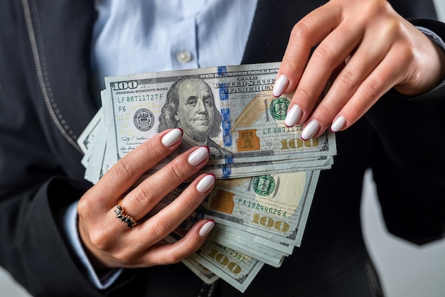 Young girl holds a large sum of dollars in her hands and counts money in a black purse