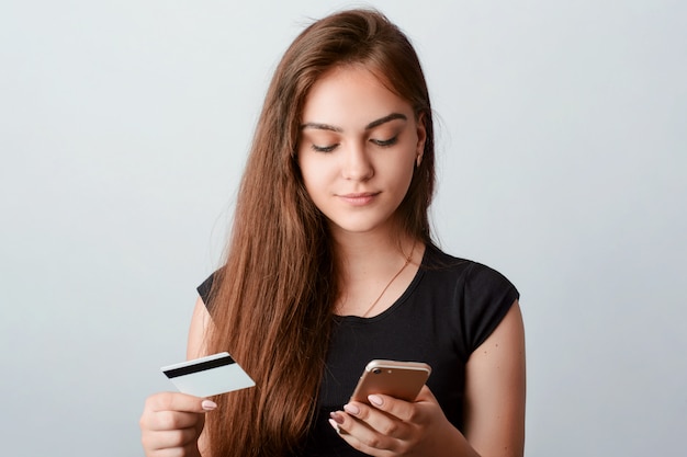 Young girl holds mobile phone and credit card