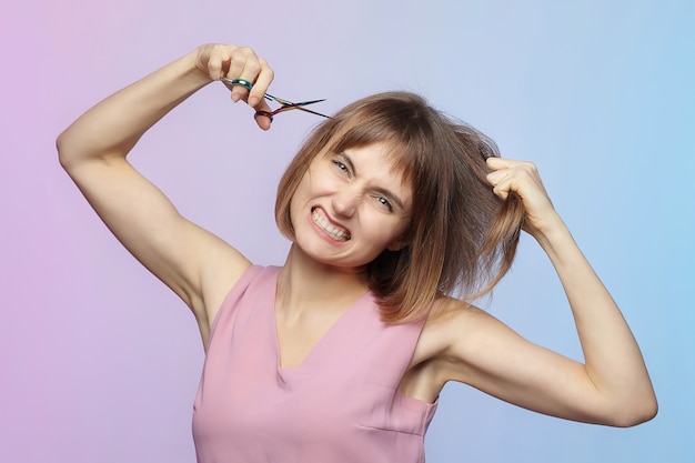 Young girl holds a pair of scissors in her hand and is about to get a haircut