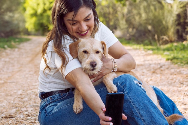 Young girl hugging her dog and taking a picture with her cell phone