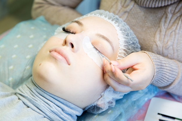 A young girl increases eyelashes in a beauty salon.