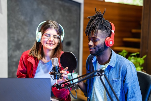 Young girl interviewing an african american rap artist live streaming a web radio broadcast using modern technologies