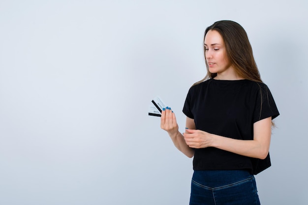 Young girl is holding credit cards and looking them on white background