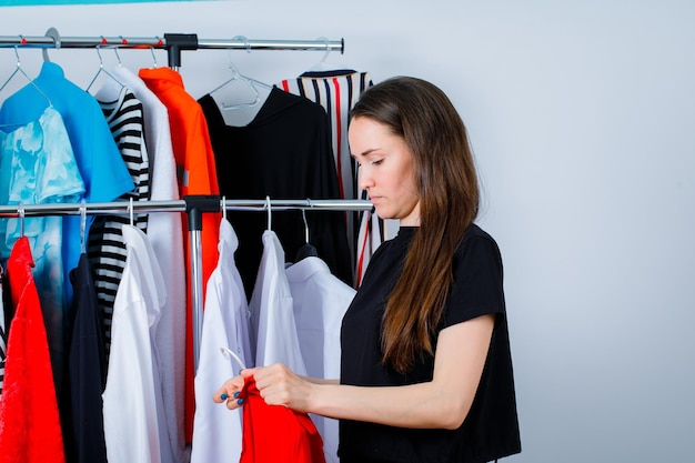 Young girl is looking at blouse's size on clothes background