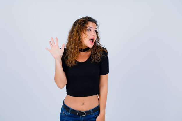 Young girl is looking up by showing hi gesture on white background