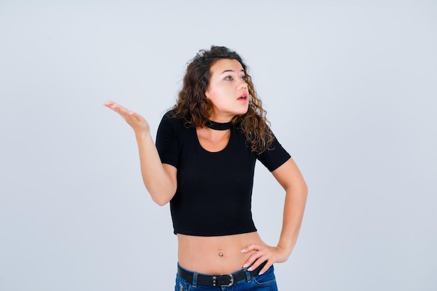 Young girl is looking up and raising up her hand on white background