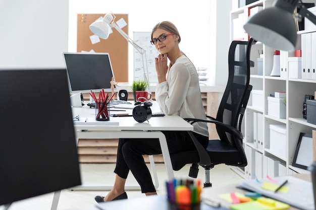 A young girl is sitting at the computer desk in the office.